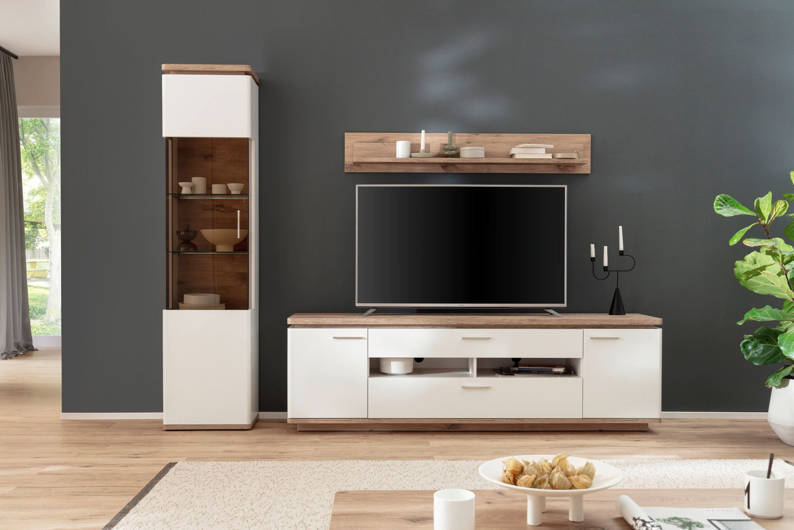 Moderne Wandkombination mit weißem und holzfarbenem Design, bestehend aus einem hohen Schrank, einem TV-Board und einem Wandregal, frontal betrachtet.