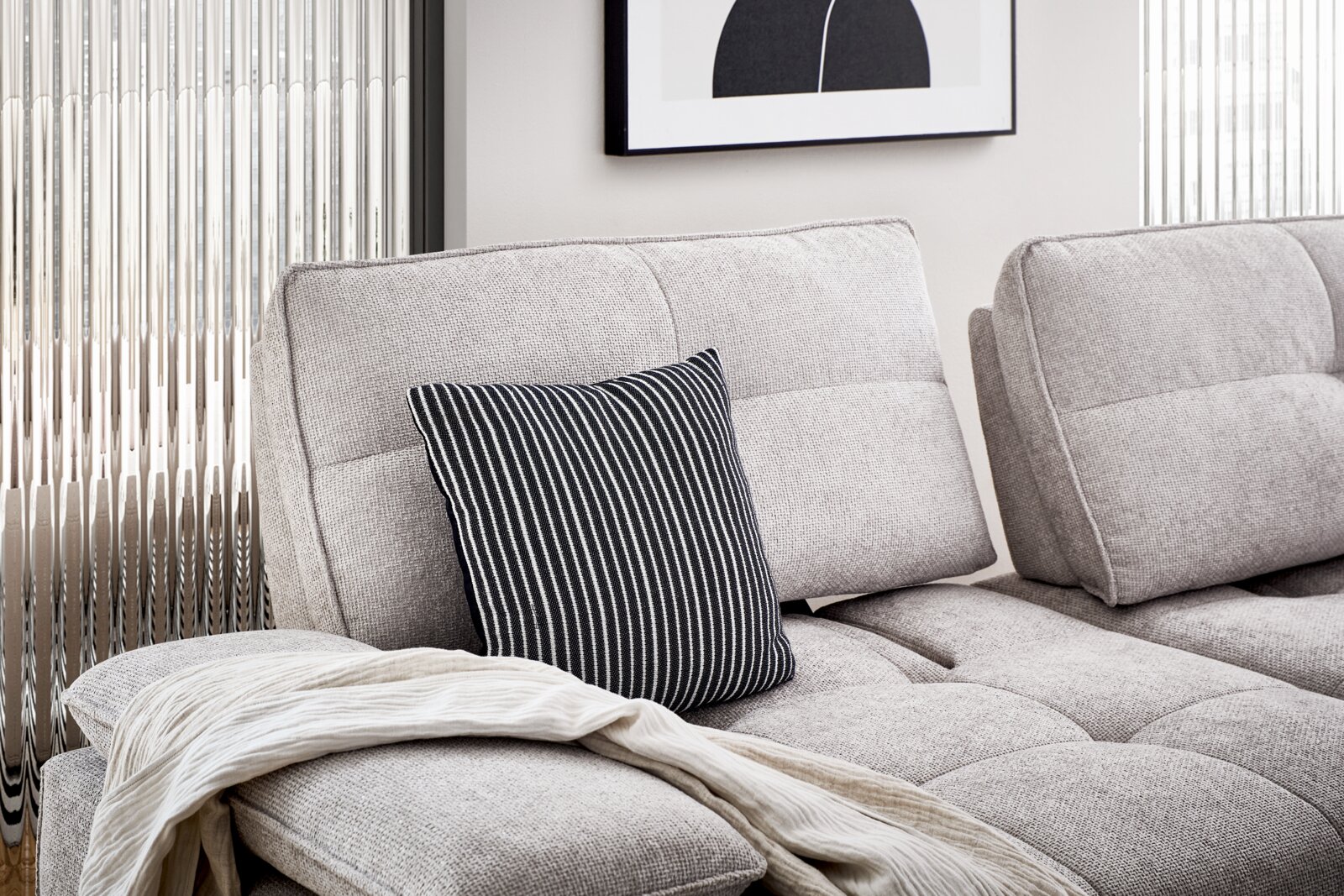 Bequeme Longchairkombination in hellem Stoff mit gestreiftem Kissen und Decke, seitliche Perspektive.