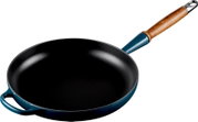 Turquoise gietijzeren koekenpan met zwarte binnenkant, houten steel en extra zijgreep, schuin van boven gefotografeerd op witte achtergrond