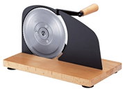 Manuelle Aufschnittmaschine mit großem Edelstahl-Rundmesser, schwarzer Metallführung und Holzkurbel auf Holzsockel, freigestellt auf Weiß, seitliche Perspektive von rechts