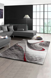 Moderner Teppich mit abstraktem Design in Schwarz, Weiß und Rot in einem stilvollen Wohnzimmer, Perspektive von oben.