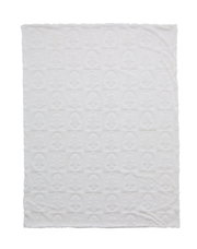 Weiße Kuscheldecke mit geprägtem Muster aus Weihnachtsbäumen und Gesichtern, von oben betrachtet.