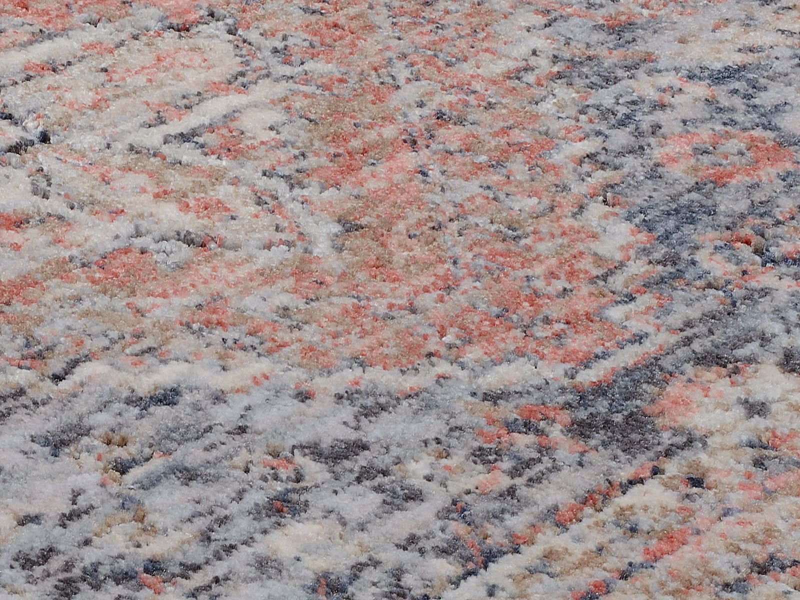 Nahaufnahme eines Frisé-Teppichs mit einem bunten, abstrakten Muster in Rot-, Blau- und Beigetönen. Die Perspektive zeigt die Textur und das Detail des Teppichs.