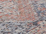 Nahaufnahme eines Frisé-Teppichs mit einem bunten, abstrakten Muster in Rot-, Blau- und Beigetönen. Die Perspektive zeigt die Textur und das Detail des Teppichs.