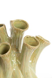 Nahaufnahme einer grünen, organisch geformten Vase mit mehreren Röhren, die an Korallen erinnern. Die Perspektive zeigt die Vase von oben.