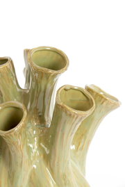 Nahaufnahme einer grünen, organisch geformten Vase mit mehreren Röhren, die an Korallen erinnern. Die Perspektive zeigt die Vase von oben.