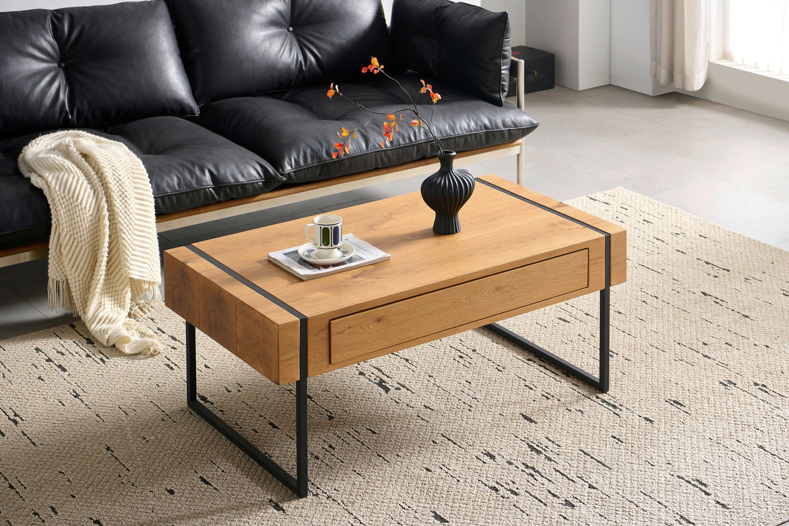 Moderner Couchtisch aus Holz mit schwarzen Metallbeinen, dekoriert mit einer Vase und einer Tasse, aus der Perspektive eines Wohnzimmers mit schwarzem Ledersofa.