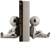 Zwei silberne Buchstützen in Form von sitzenden Figuren, die Bücher aufrecht halten. Perspektive von der Seite.