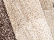 Nahaufnahme eines strukturierten Teppichs in Beige- und Brauntönen, perspektivisch von der Seite aufgenommen.