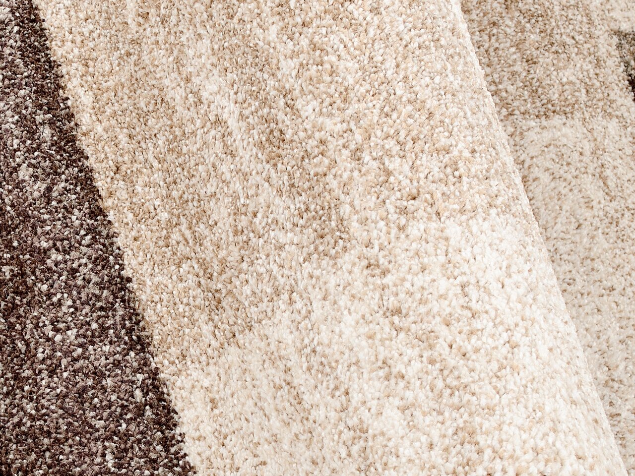 Nahaufnahme eines strukturierten Teppichs in Beige- und Brauntönen, perspektivisch von der Seite aufgenommen.