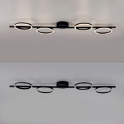 Moderne schwarze LED-Deckenleuchte mit vier ringförmigen Lichtquellen an einer geraden Schiene, warmweiß leuchtend, Ansicht von unten (Untersicht) an der Decke montiert.