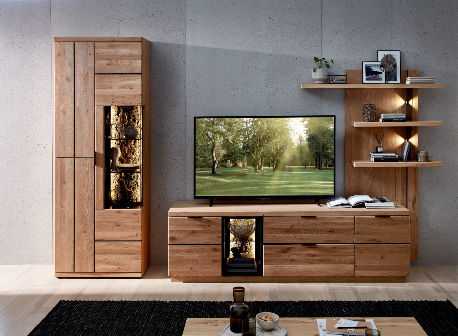 Cantus Wandkombination DONNA Wohnwand aus massivem Holz mit Vitrine, TV-Lowboard und Wandregal mit integrierter Beleuchtung, frontal in einem modernen Wohnzimmer arrangiert