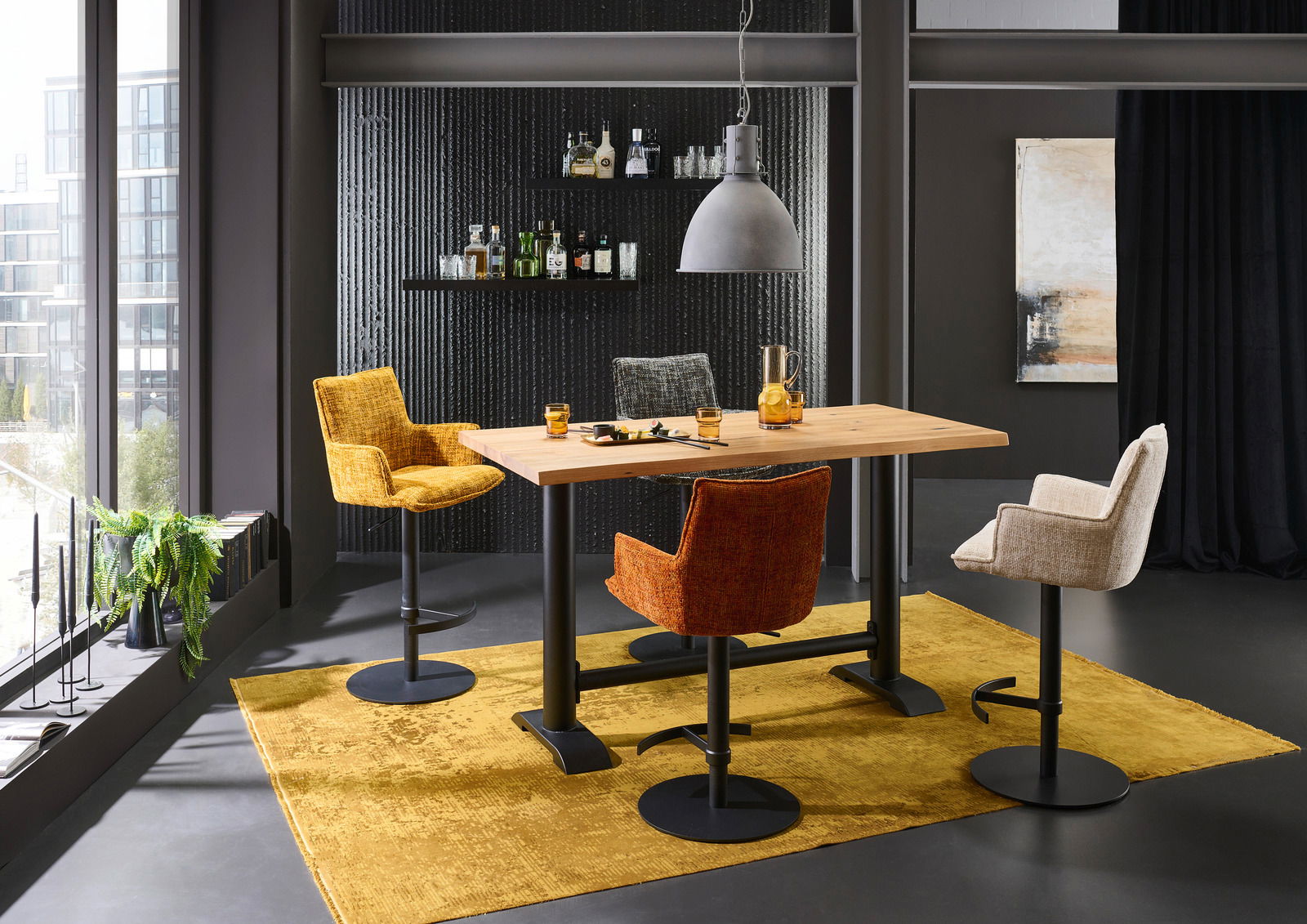 Moderner Tresentisch mit vier bunten Barhockern in einem stilvollen Raum, seitliche Perspektive.