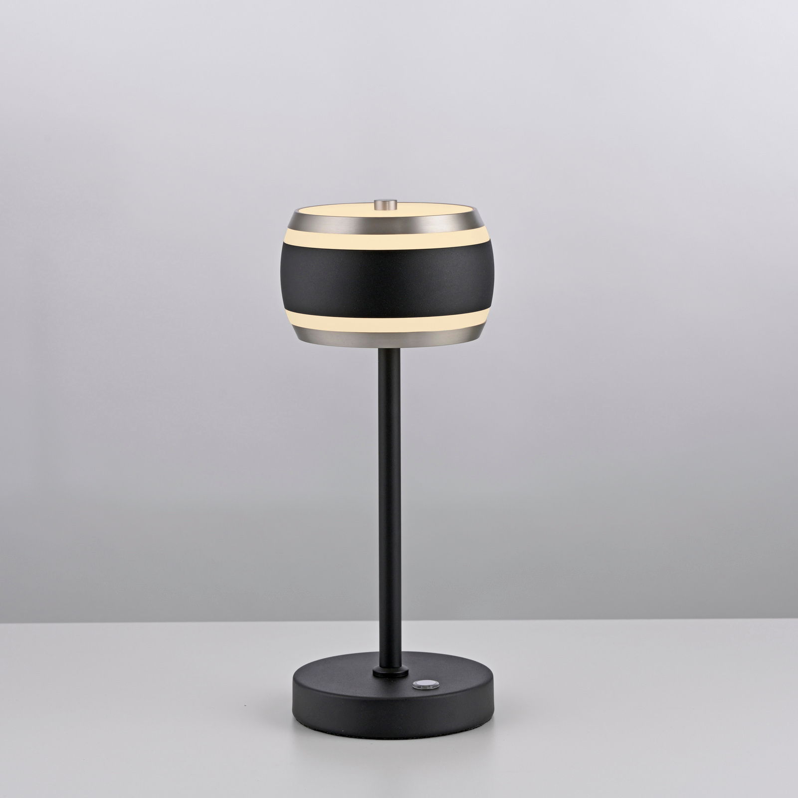 Moderne Akku-Tischleuchte in Schwarz mit zylindrischem Lampenschirm, seitliche Ansicht.