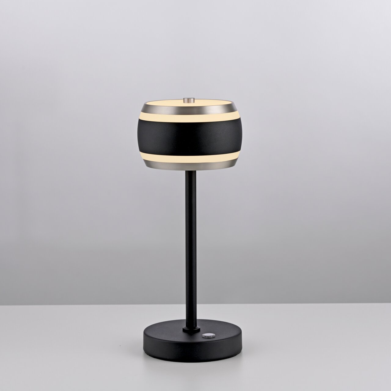 Moderne Akku-Tischleuchte in Schwarz mit zylindrischem Lampenschirm, seitliche Ansicht.