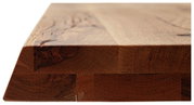 Nahaufnahme einer massiven Holz-Tischplatte mit natürlicher Maserung, seitliche Perspektive.