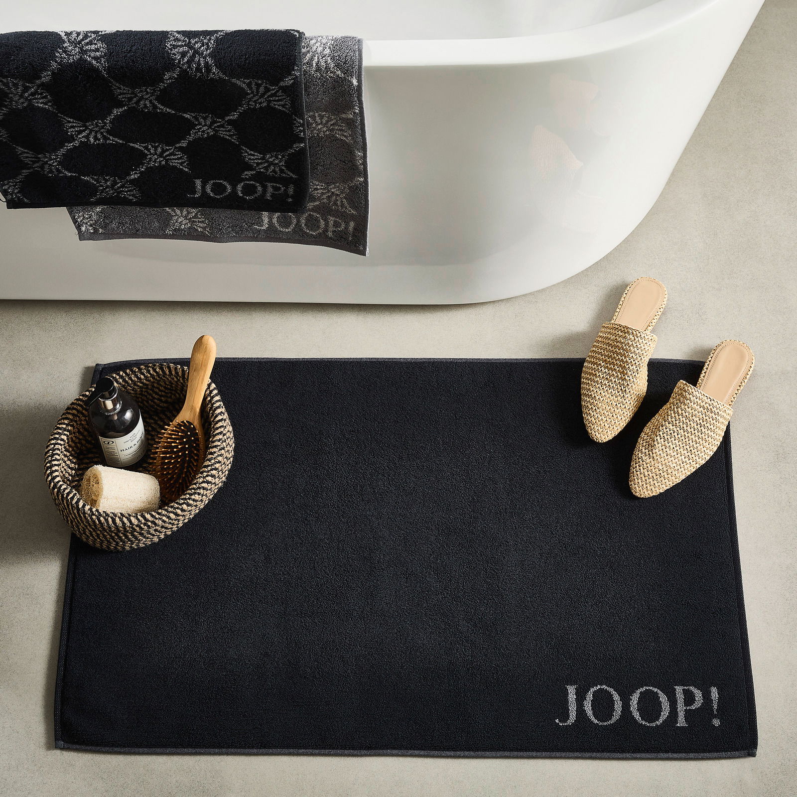 JOOP! Badematte DOUBLEFACE JOOP! Badematte DOUBLEFACE in Schwarz, von oben fotografiert, neben einer Badewanne mit Handtüchern und einem Korb mit Pflegeprodukten.