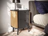 Moderne Nachtkommode mit schwarzer Oberfläche und Holzdetails, seitliche Perspektive neben einem Bett.