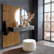 Modernes Eingangs-Set mit vertikaler Holz-Lamellenpaneel-Garderobe, rundem Wandspiegel mit indirekter Beleuchtung und schwebender grauer Konsole mit Schubladen; Perspektive: leicht schräg von vorn links im Raum aufgenommen.