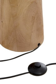 Close-up van de voet van een houten staande lamp met een zwarte voetschakelaar en kabel.