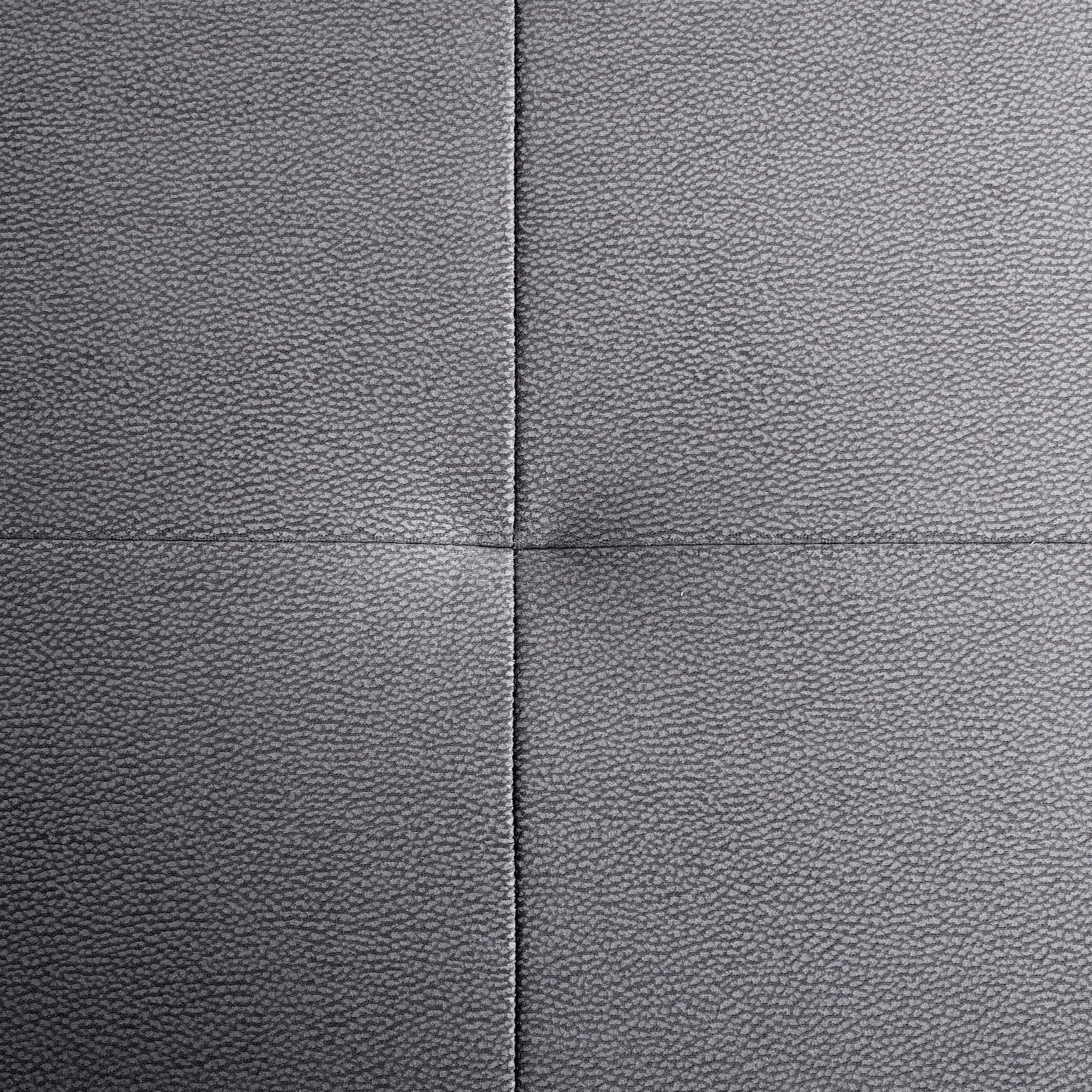 Nahaufnahme einer grauen, texturierten Polsteroberfläche mit sichtbaren Nähten in quadratischer Anordnung, von oben betrachtet.