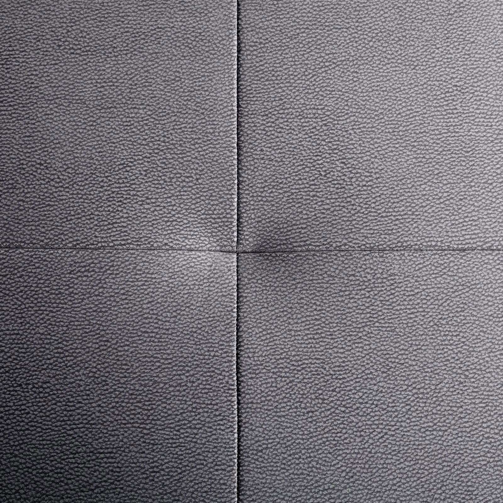 Nahaufnahme einer grauen, texturierten Polsteroberfläche mit sichtbaren Nähten in quadratischer Anordnung, von oben betrachtet.