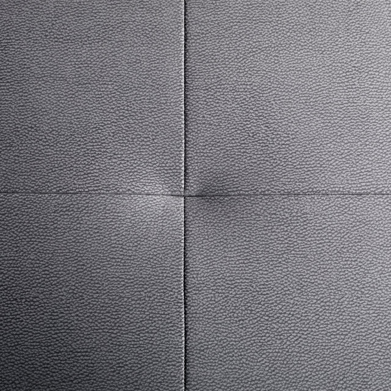 Nahaufnahme einer grauen, texturierten Polsteroberfläche mit sichtbaren Nähten in quadratischer Anordnung, von oben betrachtet.
