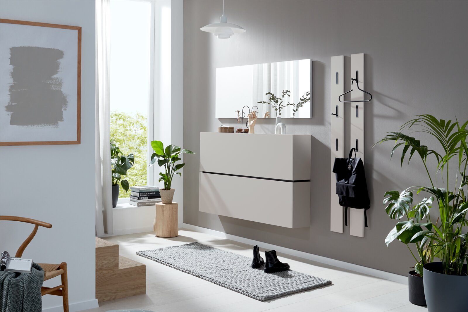 Frontale Raumansicht einer modernen, lichtdurchfluteten Diele mit schwebendem weißem Schuhschrank, großem Wandspiegel und schlanken Garderobenpaneelen.