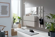 Frontale Raumansicht einer modernen, lichtdurchfluteten Diele mit schwebendem weißem Schuhschrank, großem Wandspiegel und schlanken Garderobenpaneelen.