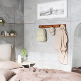 Wandgarderobe aus Holz mit Haken, an der ein Rucksack, eine Mütze und ein Hemd hängen. Perspektive: seitliche Ansicht im Schlafzimmer.