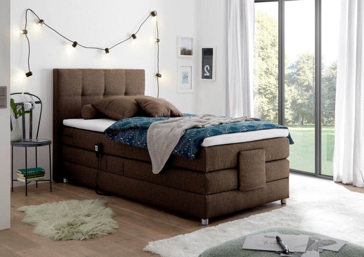 Gemütliches Boxspringbett in einem modernen Schlafzimmer, seitliche Perspektive