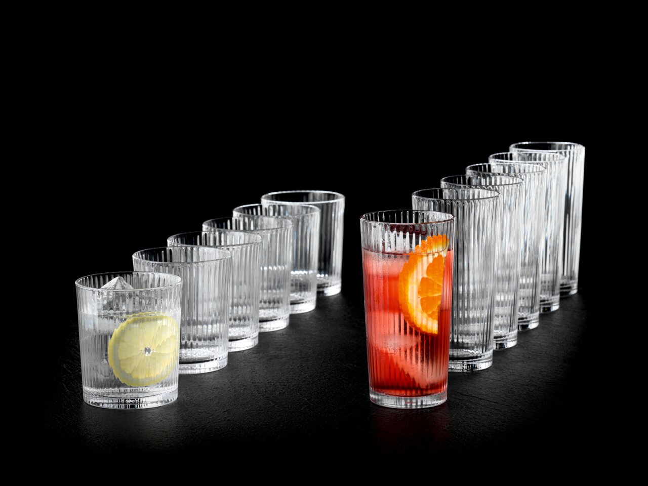 Nachtmann Becherset 12-tlg. APERITIVO Set aus zwölf gerippten Gläsern, seitliche Perspektive, gefüllt mit Getränken und Zitrusfrüchten.