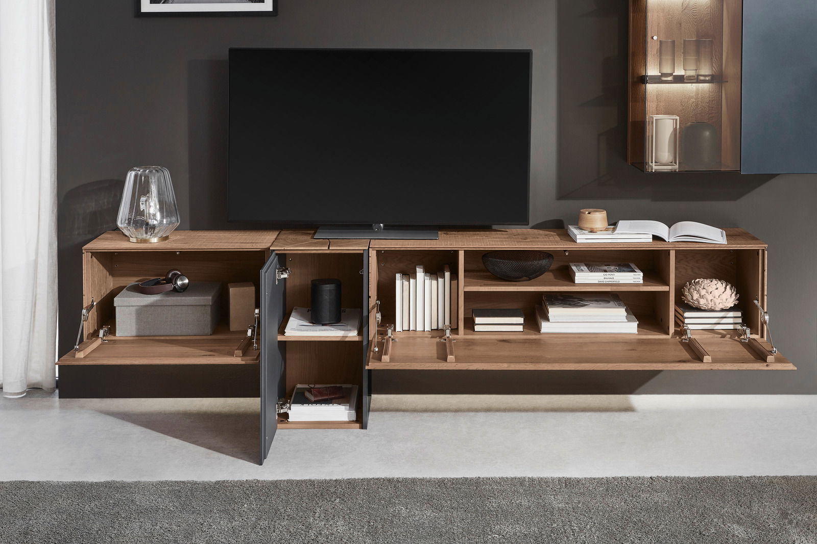 Moderne Wandkombination aus Holz mit offenen und geschlossenen Fächern, dekoriert mit Büchern und Accessoires, frontal betrachtet.