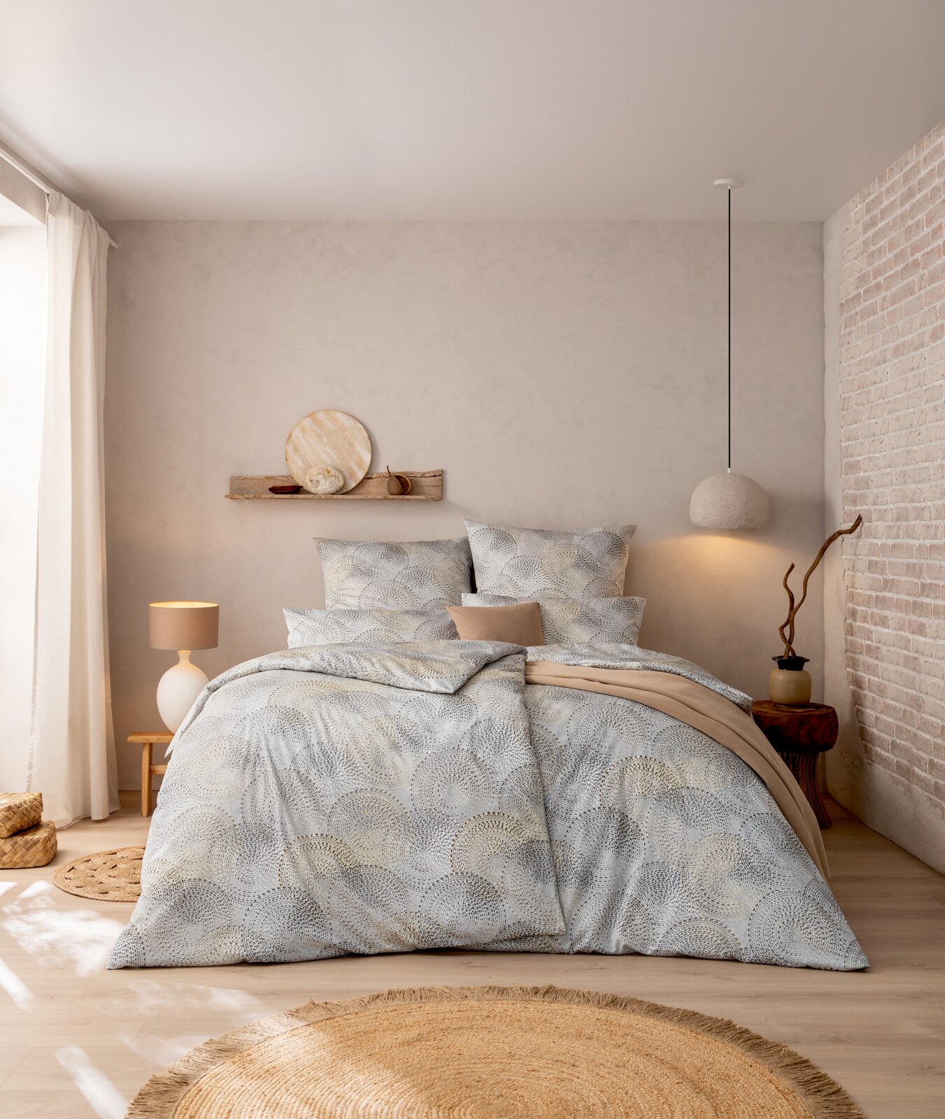Estella Mako-Satin Bettwäsche 135x200cm ORION Modernes Schlafzimmer mit Bettwäsche-Set in Grau-Beige mit kreisförmigem Muster, dekorativen Kissen und beigefarbener Decke; frontal aus leicht erhöhter Perspektive aufgenommen.