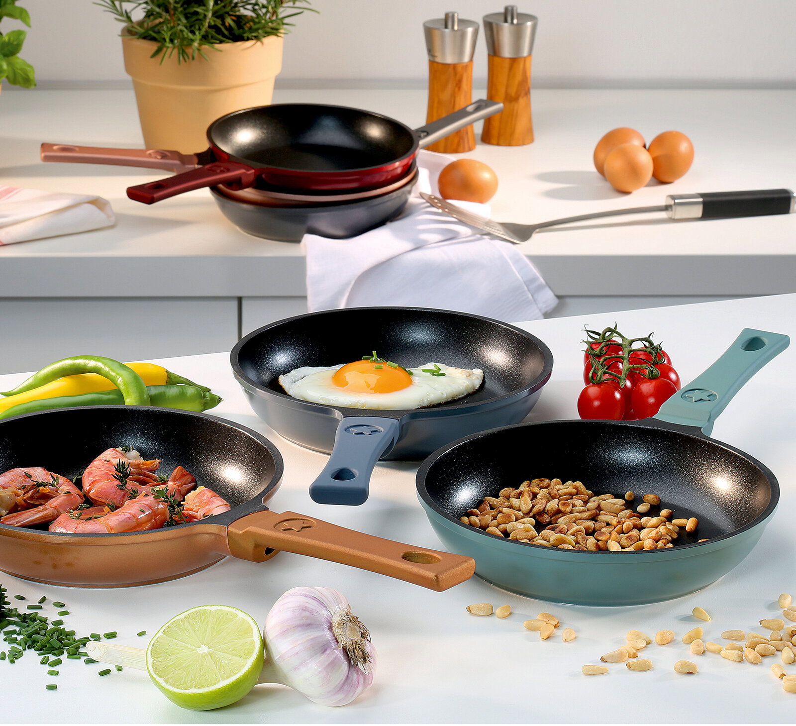 Spring Mini Bratpfanne CLASSIC Verschiedene Mini Bratpfannen CLASSIC 18 cm in verschiedenen Farben, gefüllt mit Speisen wie Spiegelei, Garnelen und Nüssen, auf einer Küchenarbeitsplatte von oben betrachtet.