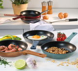 Verschiedene Mini Bratpfannen CLASSIC 18 cm in verschiedenen Farben, gefüllt mit Speisen wie Spiegelei, Garnelen und Nüssen, auf einer Küchenarbeitsplatte von oben betrachtet.