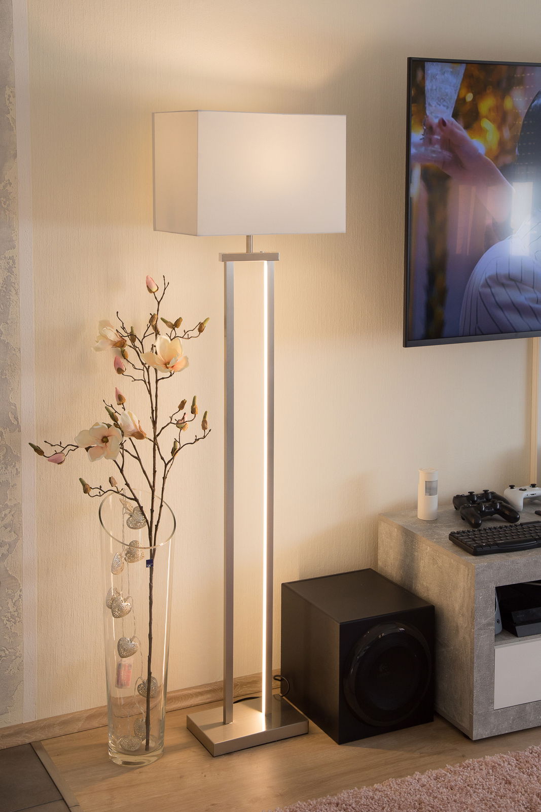 NOWA Stehleuchte SYDNEY Moderne Stehleuchte mit rechteckigem Lampenschirm in einem gemütlichen Wohnzimmer, seitliche Perspektive.