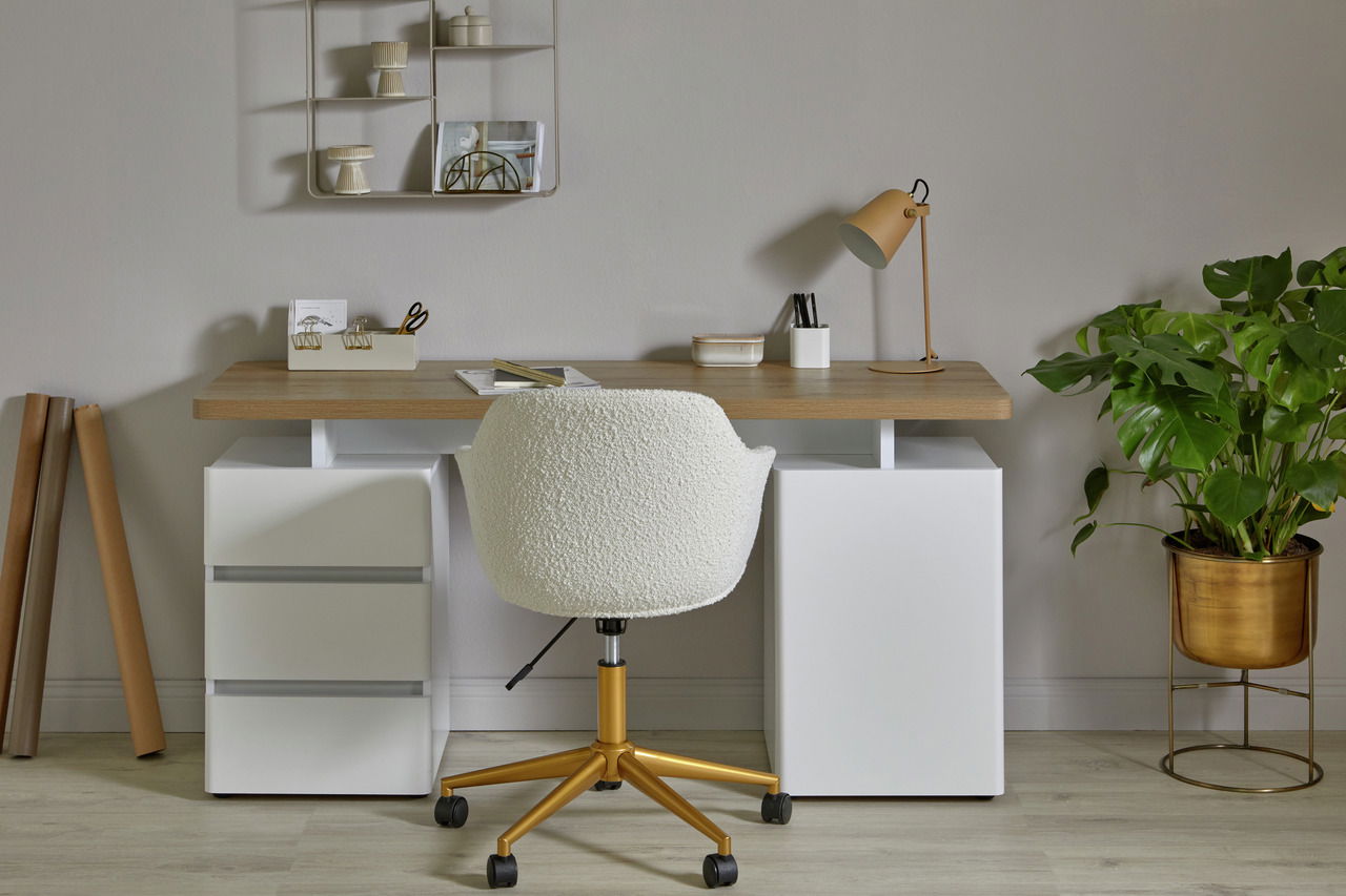 Rückansicht eines modernen Bürostuhls mit weißem Stoffbezug und goldener Basis auf Rollen, vor einem Schreibtisch mit Holzplatte und weißen Schubladen, in einem stilvoll eingerichteten Raum.