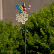 Kleurrijke decoratieve tuinprikkers in de vorm van feeën, met vlindervleugels en witte bloemen op een metalen staafje, zijaanzicht in de tuin tegen een groene achtergrond