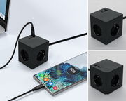 Schwarzer Steckdosenwürfel mit USB-Anschlüssen, perspektivisch von oben und seitlich gezeigt, verbunden mit einem Smartphone und einem Laptop.