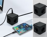 Schwarzer Steckdosenwürfel mit USB-Anschlüssen, perspektivisch von oben und seitlich gezeigt, verbunden mit einem Smartphone und einem Laptop.