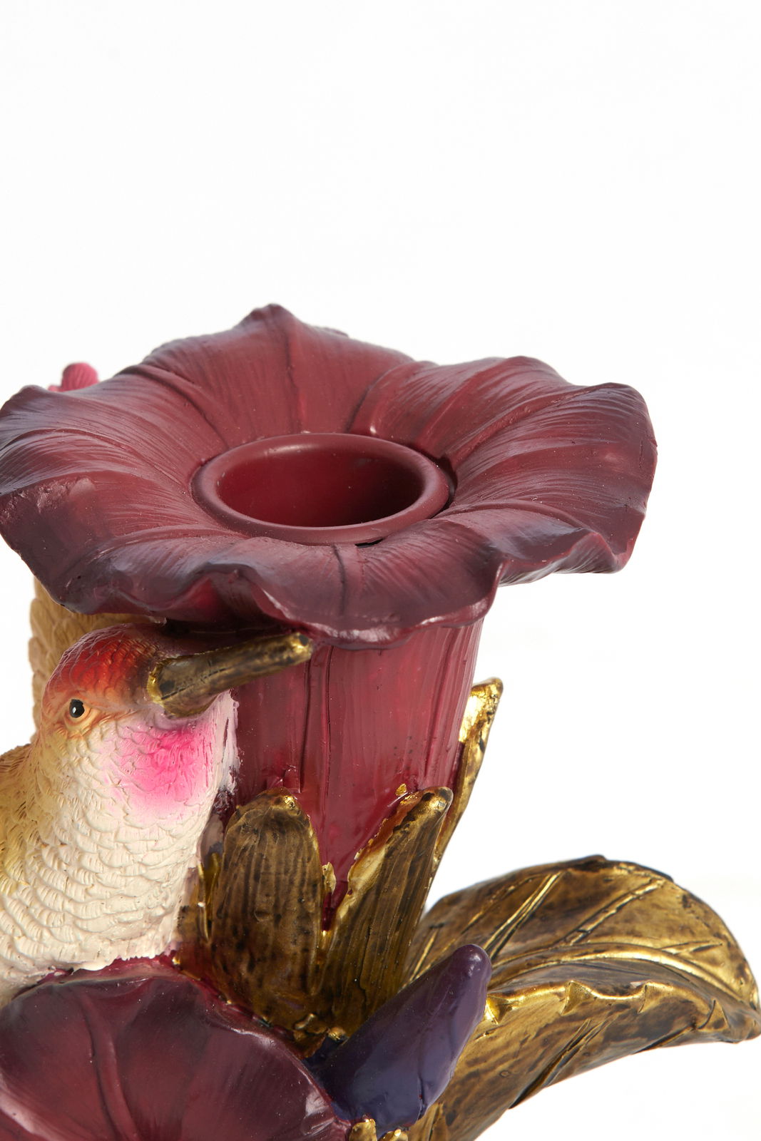 Detailansicht eines kunstvollen Kerzenständers in Form einer Blume mit einem Vogelmotiv, verziert mit goldenen Akzenten.