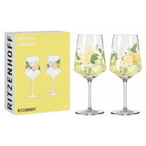 Zwei elegante Limoncello-Gläser mit Zitronen- und Blumenmotiv, frontal vor gelber Verpackung präsentiert.