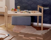 Het tafelblad van de Tiny Table in een kinderkamer, van voren gefotografeerd, met speelgoed en een tapijt eronder.