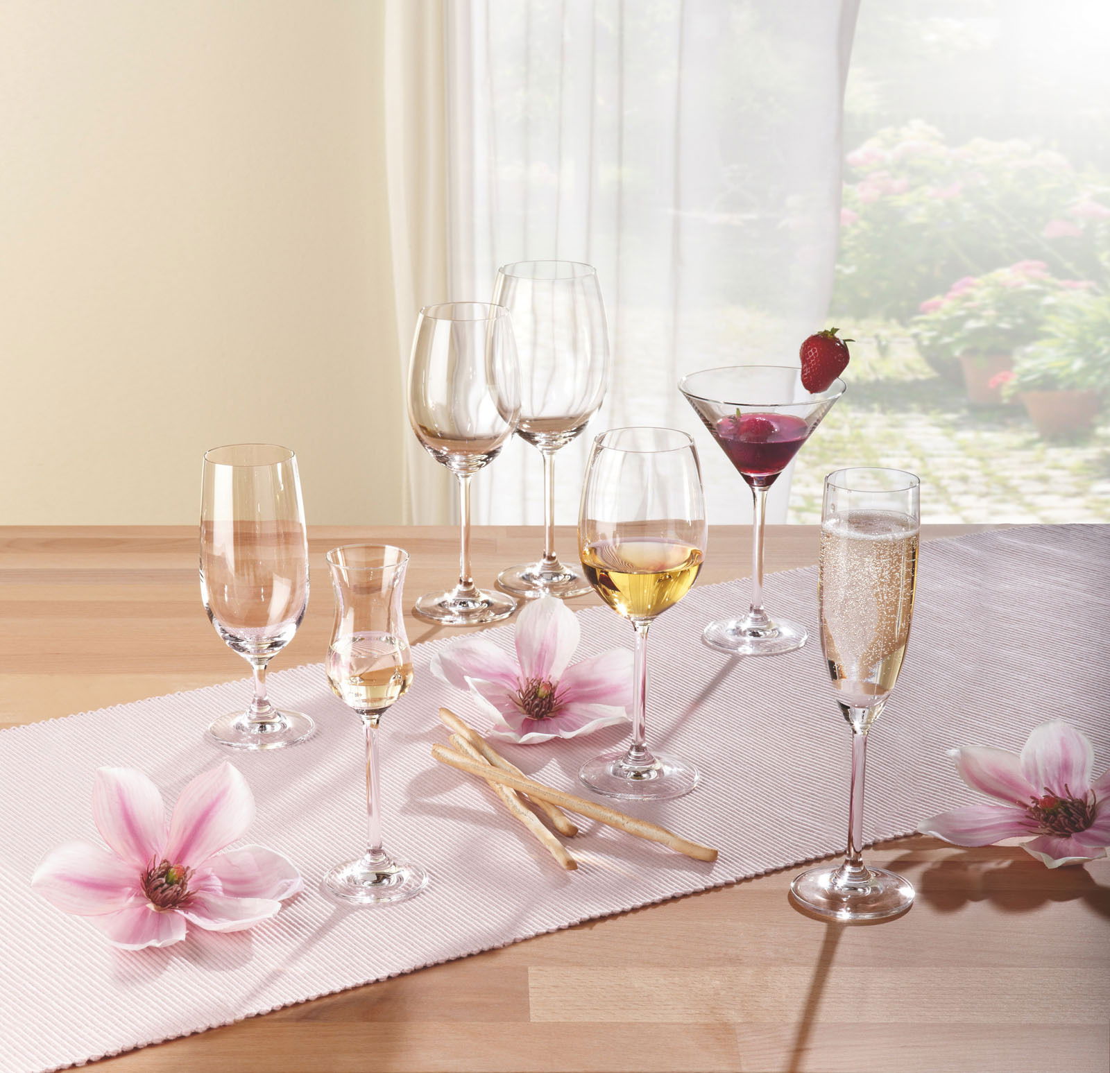 Verschiedene Gläser der Daily-Serie auf einem Tisch mit Blumen, seitliche Perspektive.