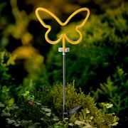 Gelbe Solar Stabbeleuchtung in Schmetterlingsform, frontal fotografiert, in einem grünen Garten platziert.