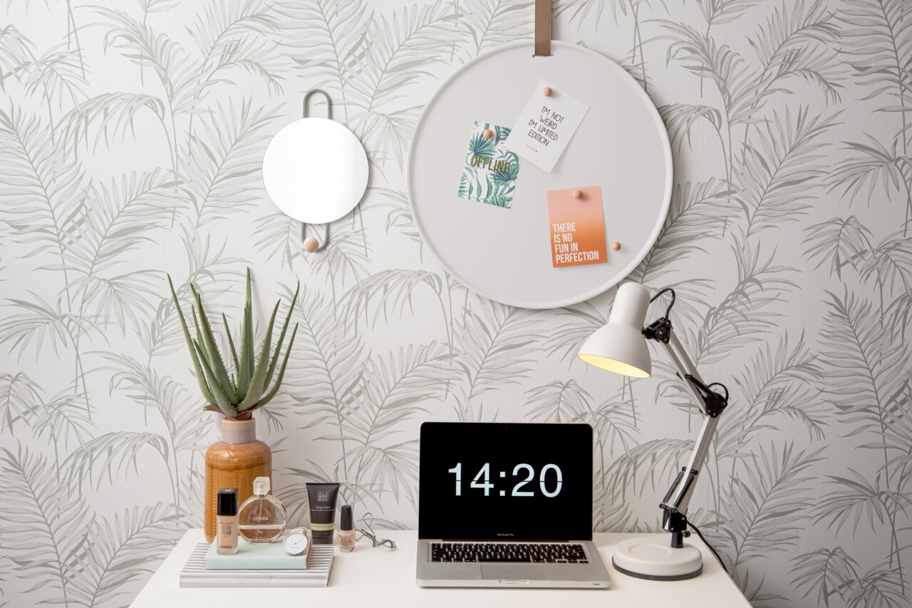 Rundes Memo-Board an der Wand mit Pflanzenmotiv, dekoriert mit Notizen und Karten, aus seitlicher Perspektive.