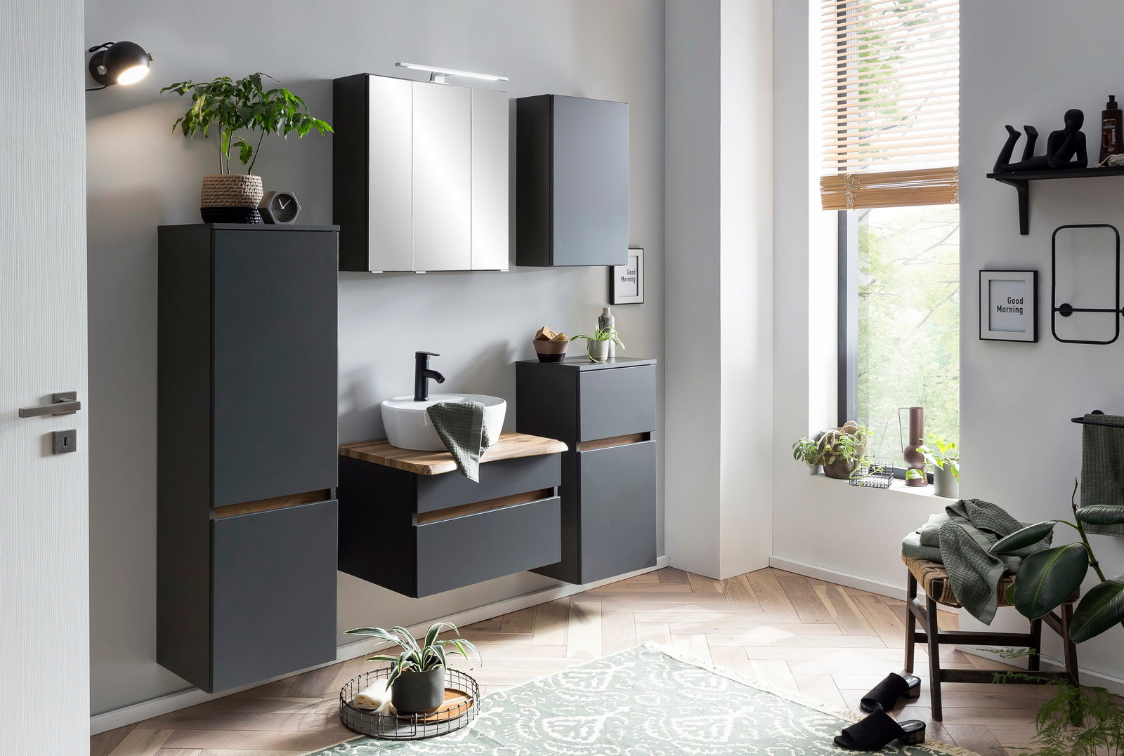 Modernes Waschtisch-Set in einem stilvollen Badezimmer mit grauen Schränken, einem Spiegel und Pflanzen, seitliche Perspektive.