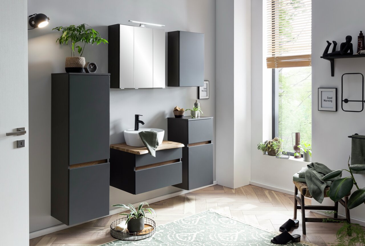 Modernes Waschtisch-Set in einem stilvollen Badezimmer mit grauen Schränken, einem Spiegel und Pflanzen, seitliche Perspektive.