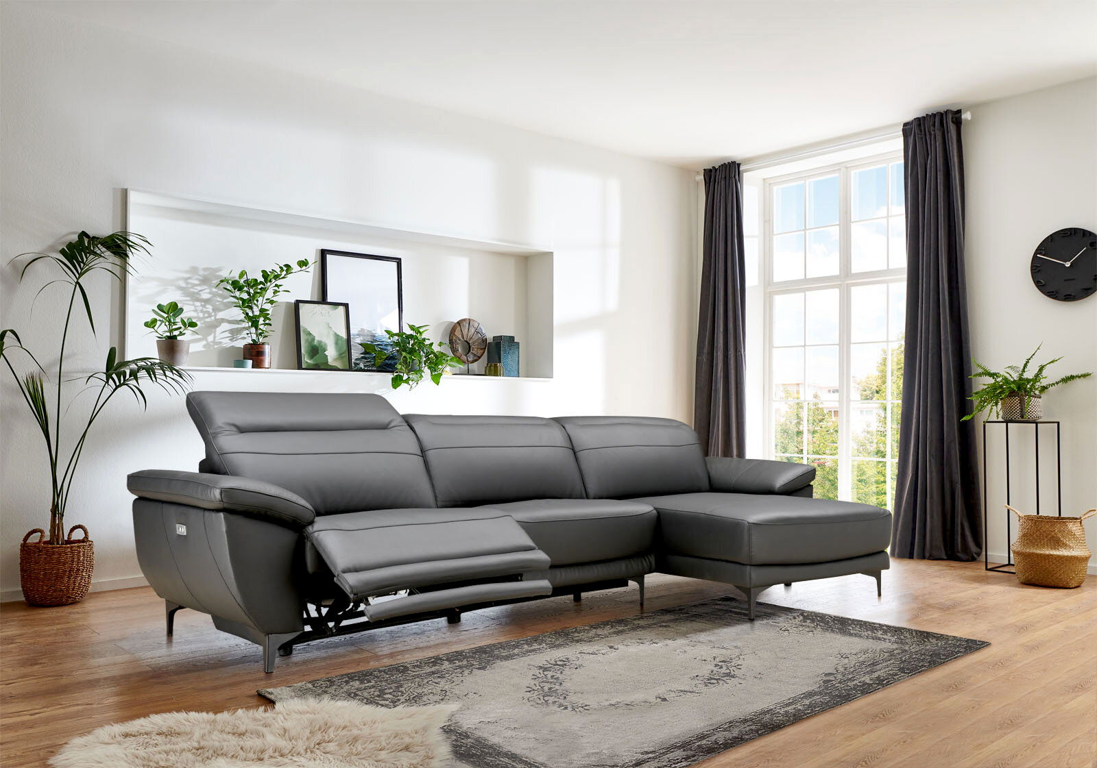 Graue Longchairkombination RONALD von XORA in einem modernen Wohnzimmer, seitliche Perspektive mit Blick auf das Sofa und die Fenster im Hintergrund.